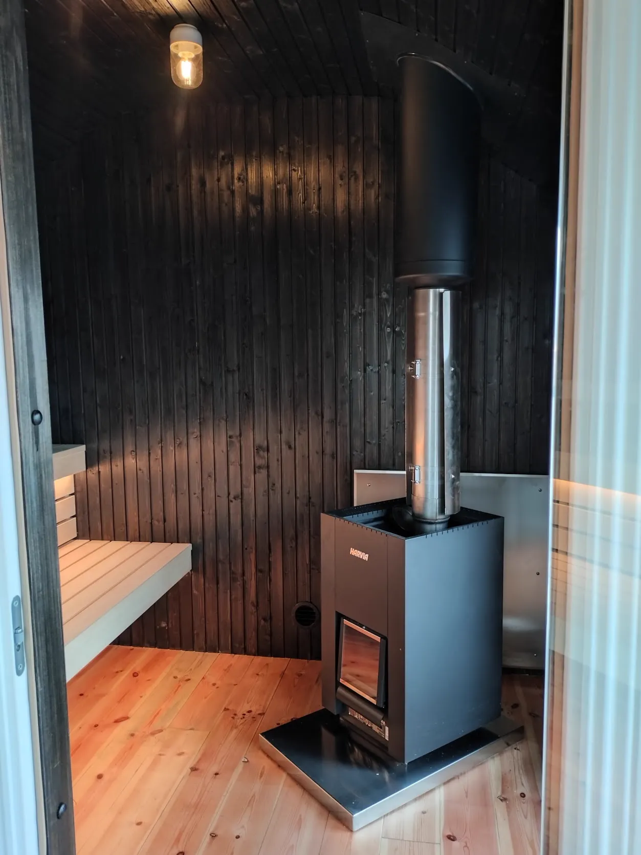 Bastu med mörk träpanel och aggregat