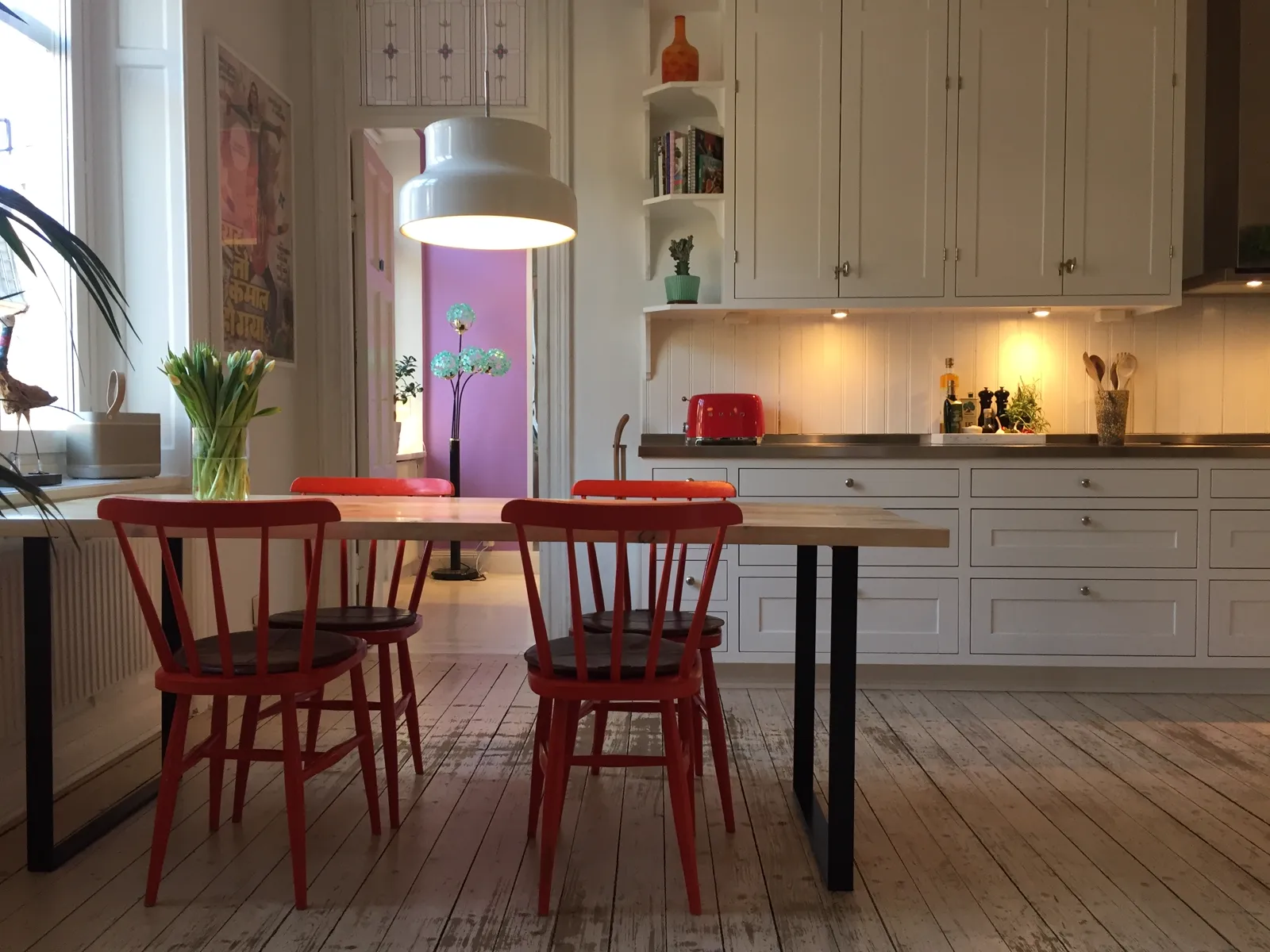 Kök med vita skåp och röda stolar